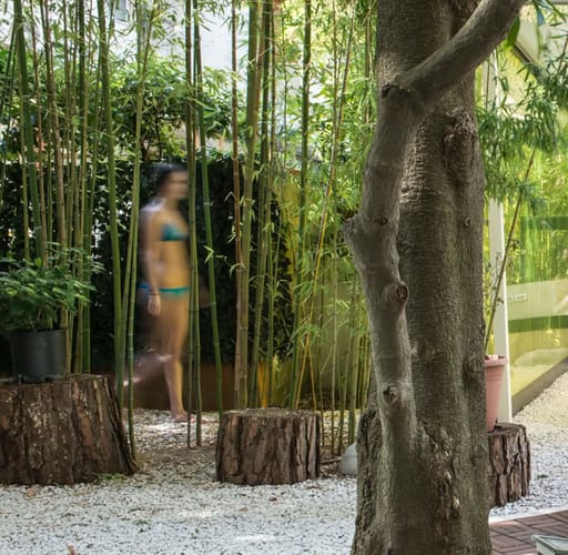 Dettaglio bamboo spa, con ragazza che cammina tra gli alberi di bamboo
