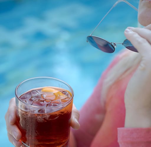 Dettaglio di una ragazza che beve un drink a bordo piscina